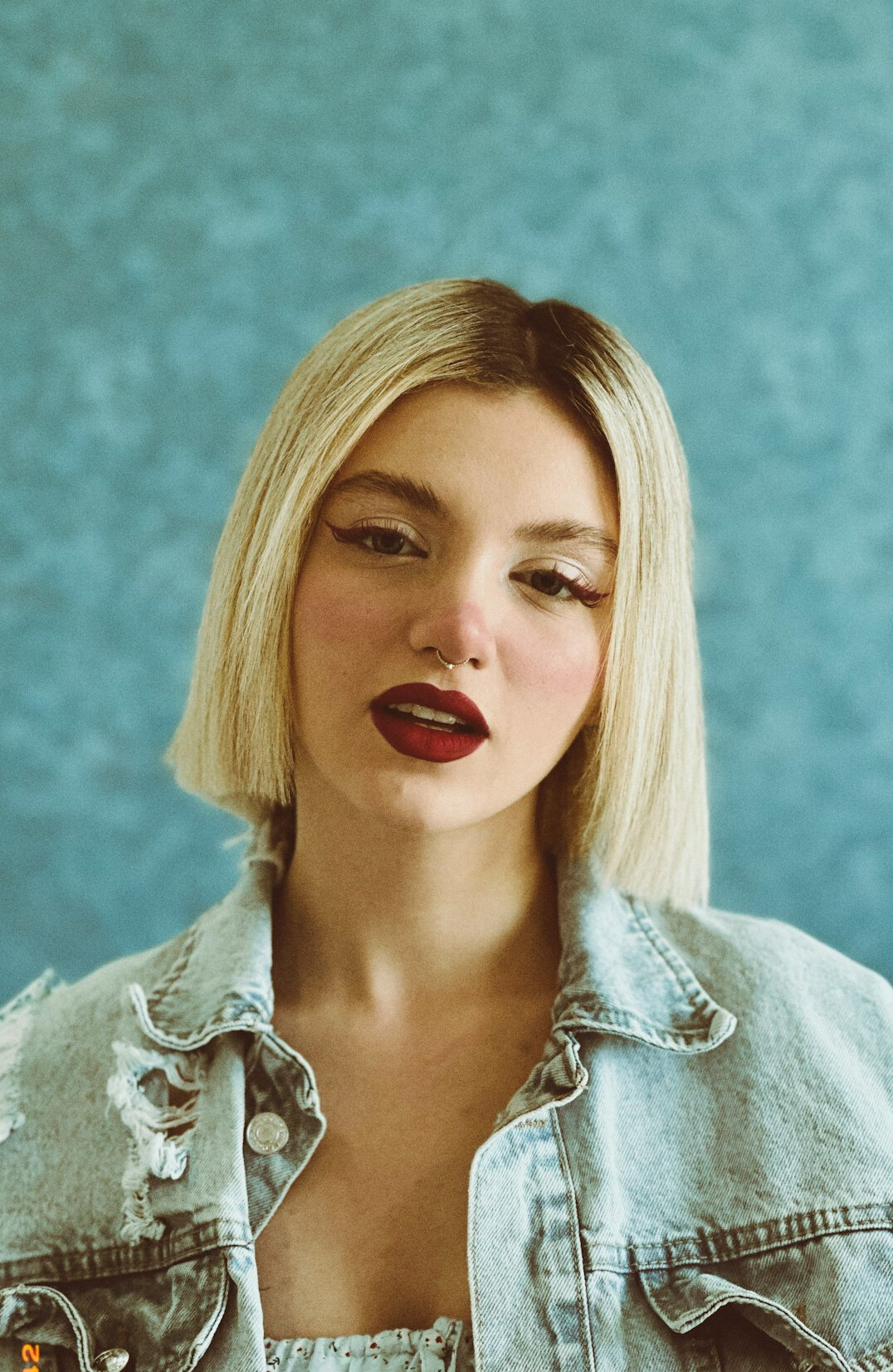Studio portrait of a young woman with straight blonde hair and a denim shirt